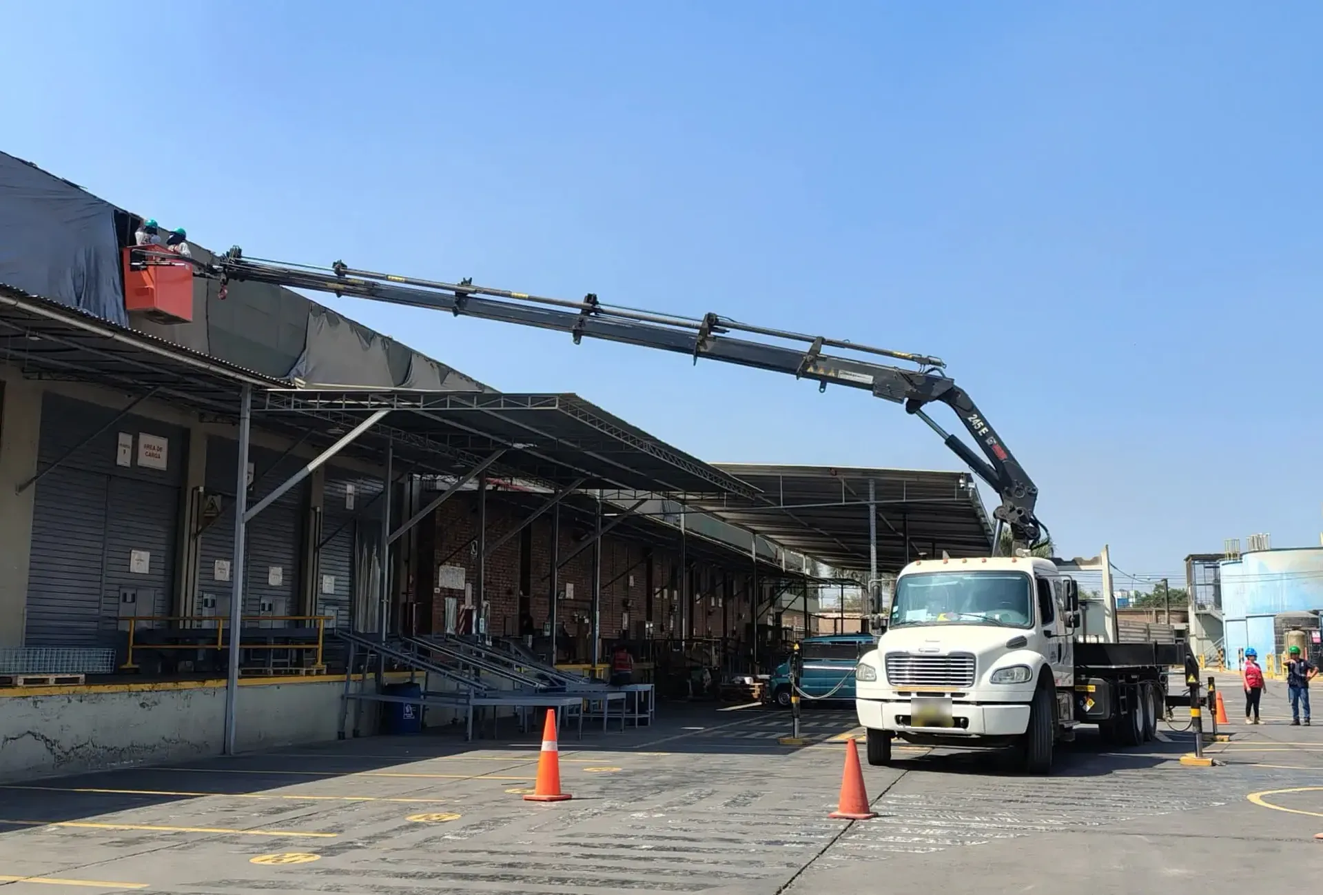 Camión grúa articulada de Grúas El Fénix en maniobra dentro de un almacén industrial